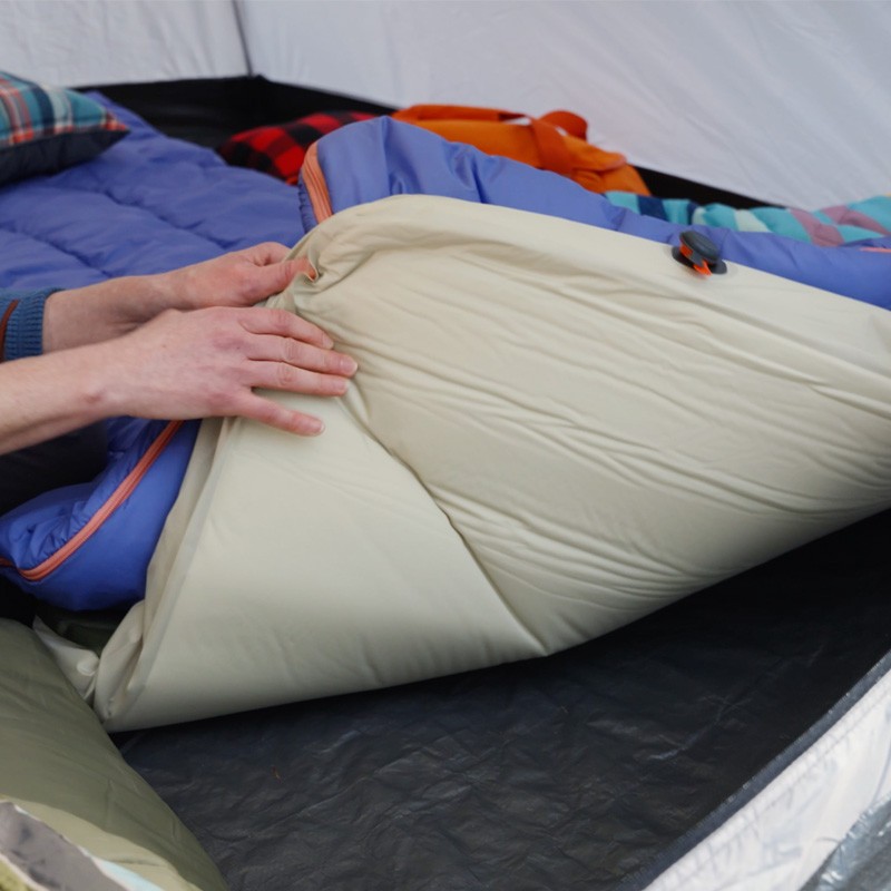 A person inside a tent inspects a L L Bean sleeping pad.