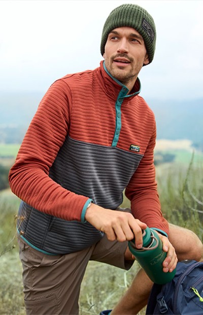 Man with water bottle hiking on a grassy trail.