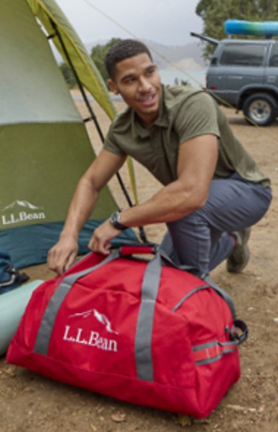 Image of man packing a duffle bag outside a tent.