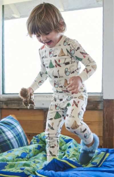 Young child in pajamas, holding a toy, jumping on the bed.