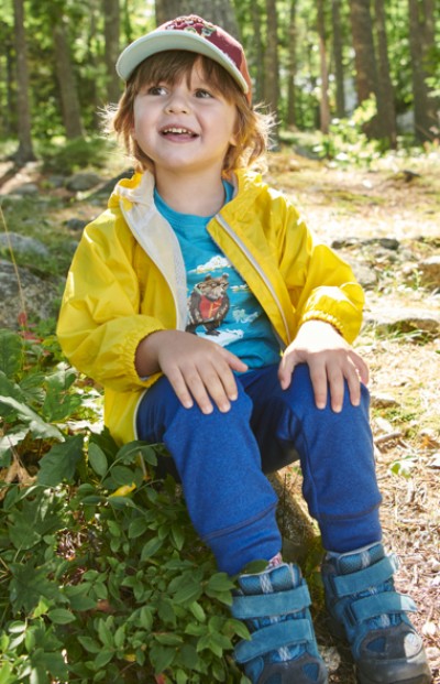 Small child wearing LL Bean clothing sitting on the ground outside.