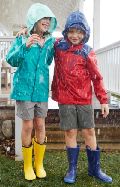 Two children weaing rain gear outside in the rain.