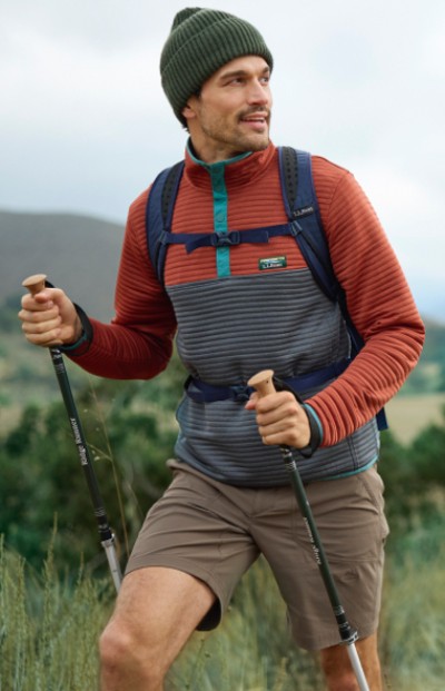 Man hiking on a grassy trail with mountains in the background.