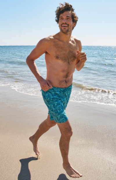 Man wearing LL Bean swim shorts, jogging on the beach.