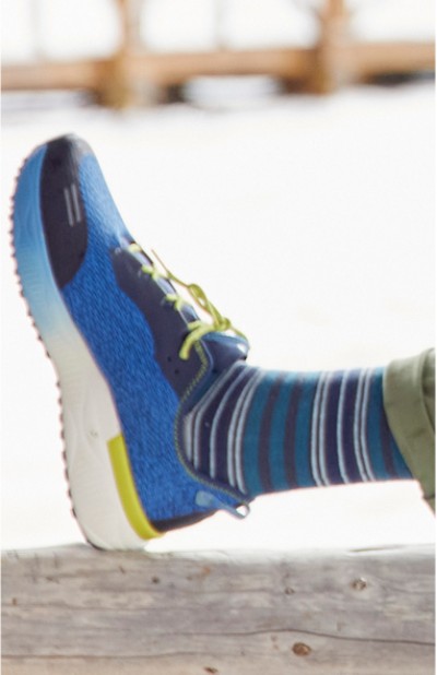 Image depicting a person wearing a sneaker with striped socks.