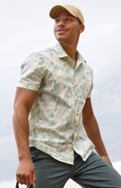 Man wearing a short sleeve shirt and a ball cap walking outside.