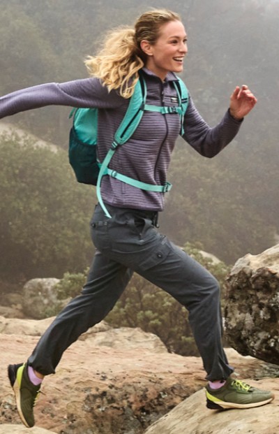 Woman wearing LL Bean activewear running on rocks.