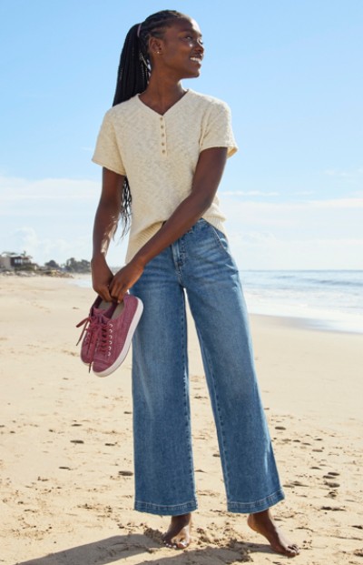 Woman wearing jeans walking on the beach at the ocean.