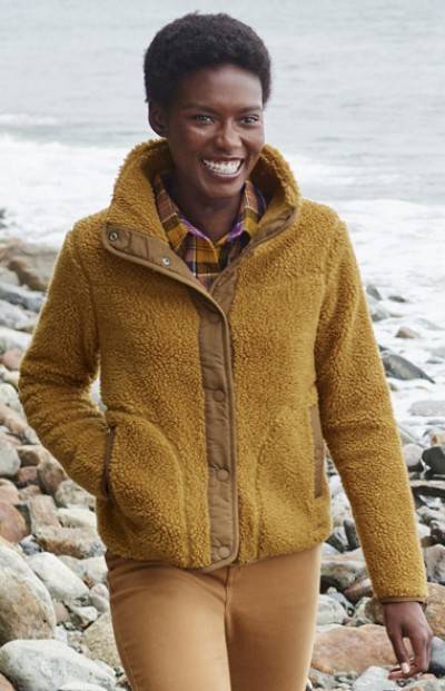 Woman wearing a fleece jacket walking by the ocean