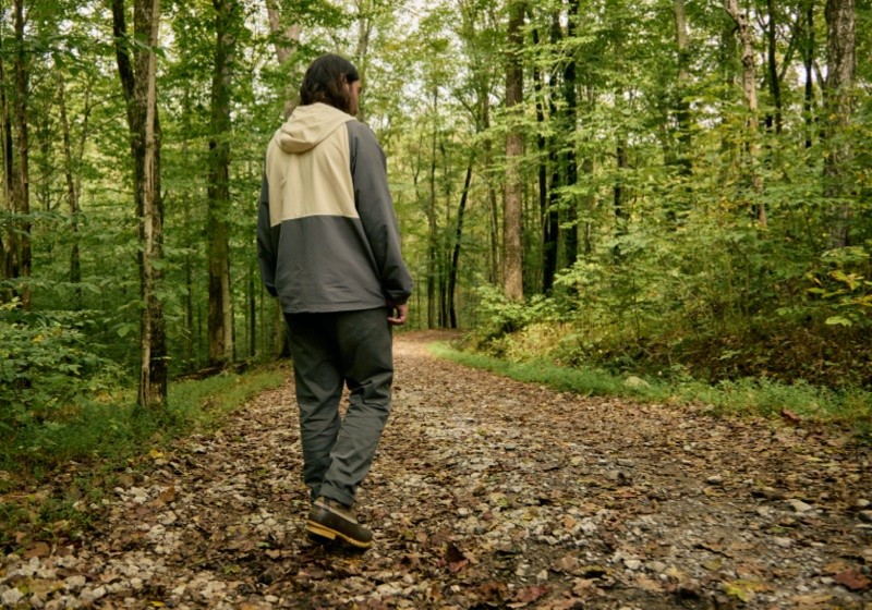 Noah Kahan walking in the woods wearing an L.L.Bean & Noah Kahan anorak.