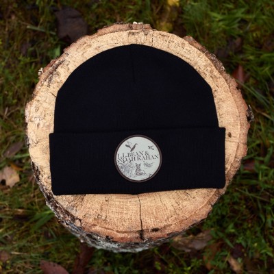 An L.L.Bean & Noah Kahan beanie on a wood stump.