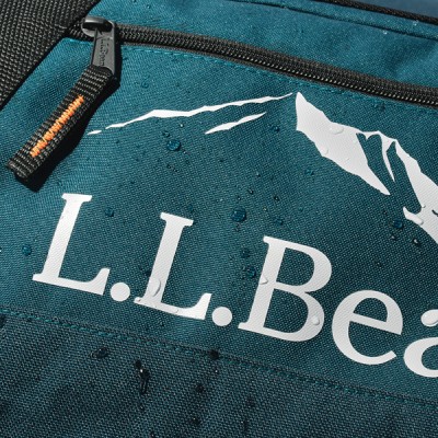 A close up image showing fabric details of a green L L Bean adventure duffle. 