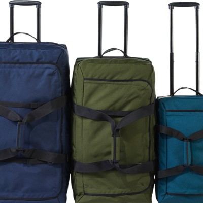 3 L L Bean rolling duffles of varying sizes and colors stand upright.