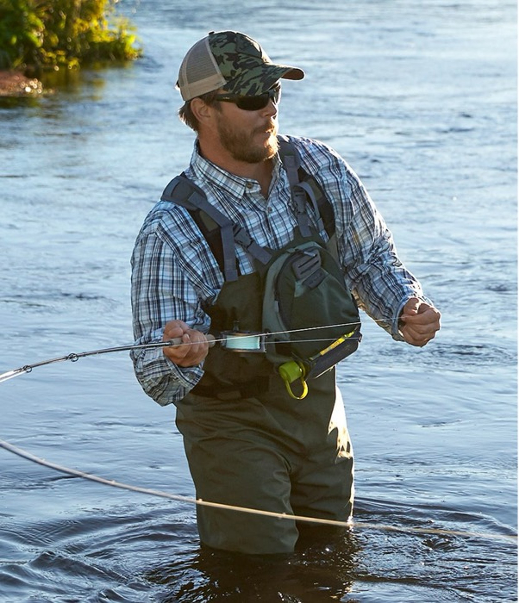 A man in waders fly fishing in a stream