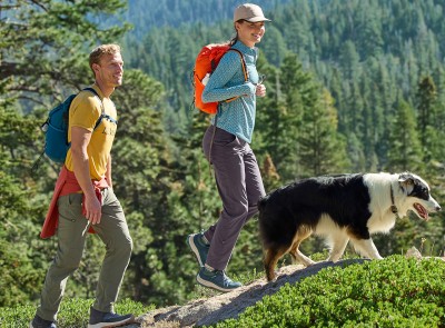2 hikers wearing large packs and using hiking poles, shot from behind, beautiful mountain scene and blue sky.