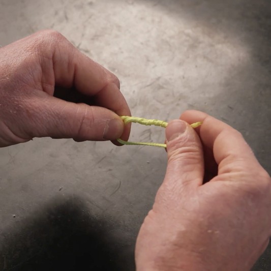 Hands wrap the tag end around both lines inside the loop about 4 to 5 times.