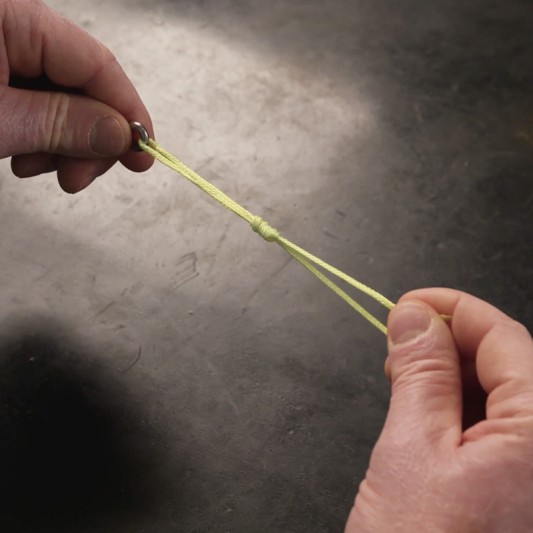 Hands partially tighten a moistened fishing line.