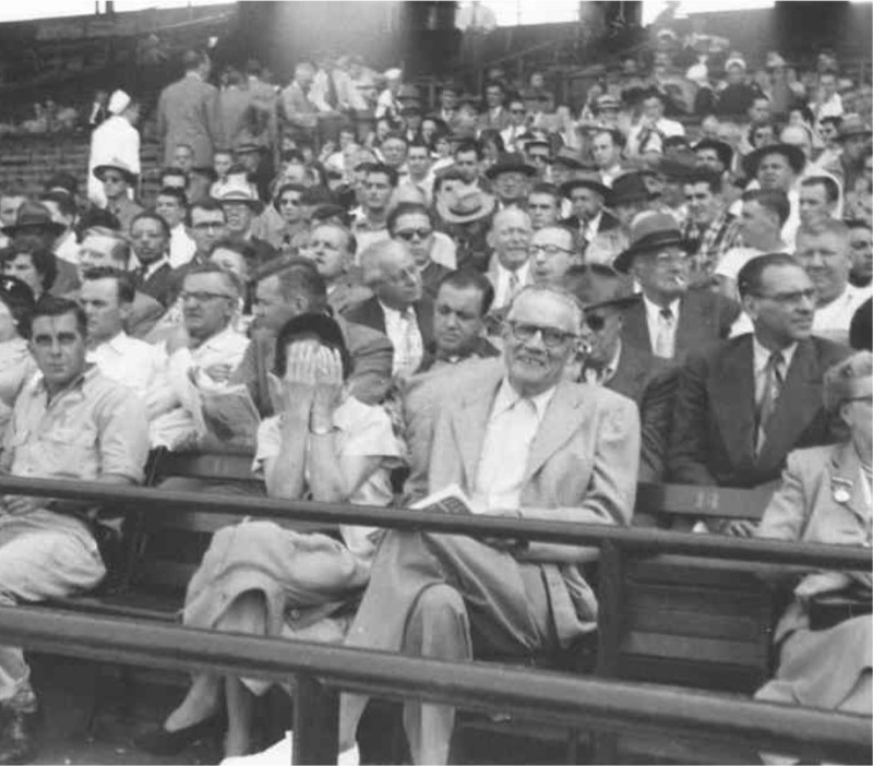 A black and white photo Tom and Jean Yawkey sitting at a crowded Fenway Park.