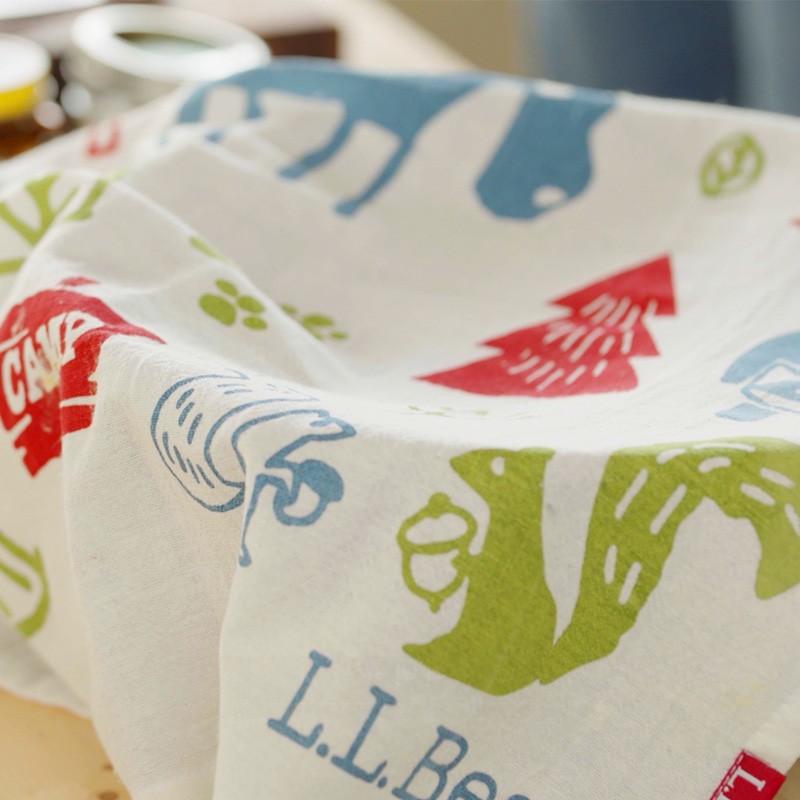 White cloth with colorful animal and tree prints, plus “L L Bean” text, draped over a mixing bowl.