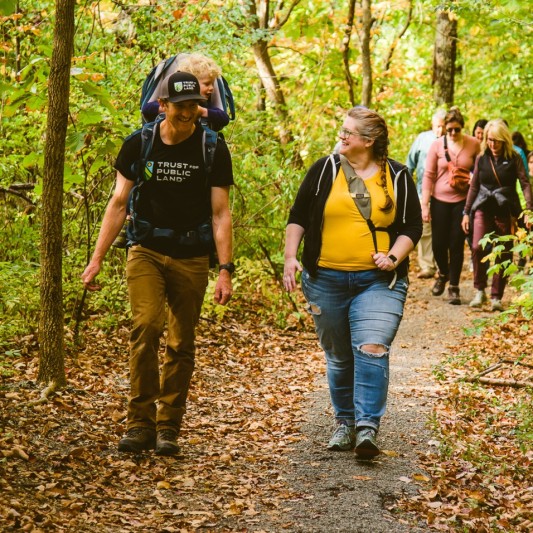 Man and woman walking on a leaf laden path.