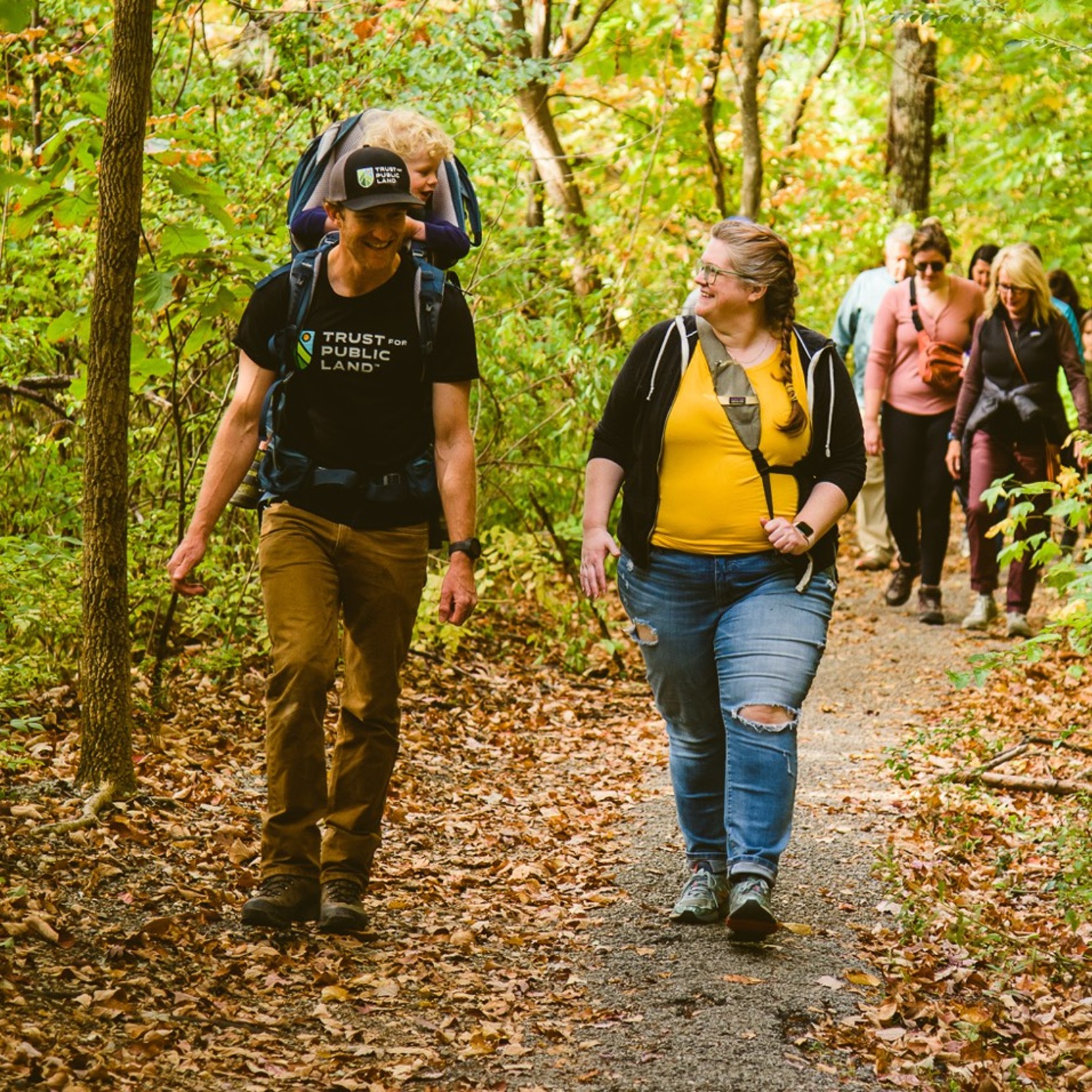 Man and woman walking on a leaf laden path.