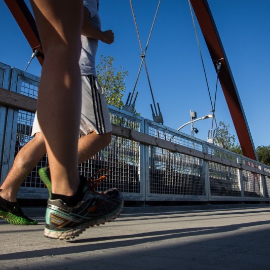 Close up of feet running on a bridge outside.
