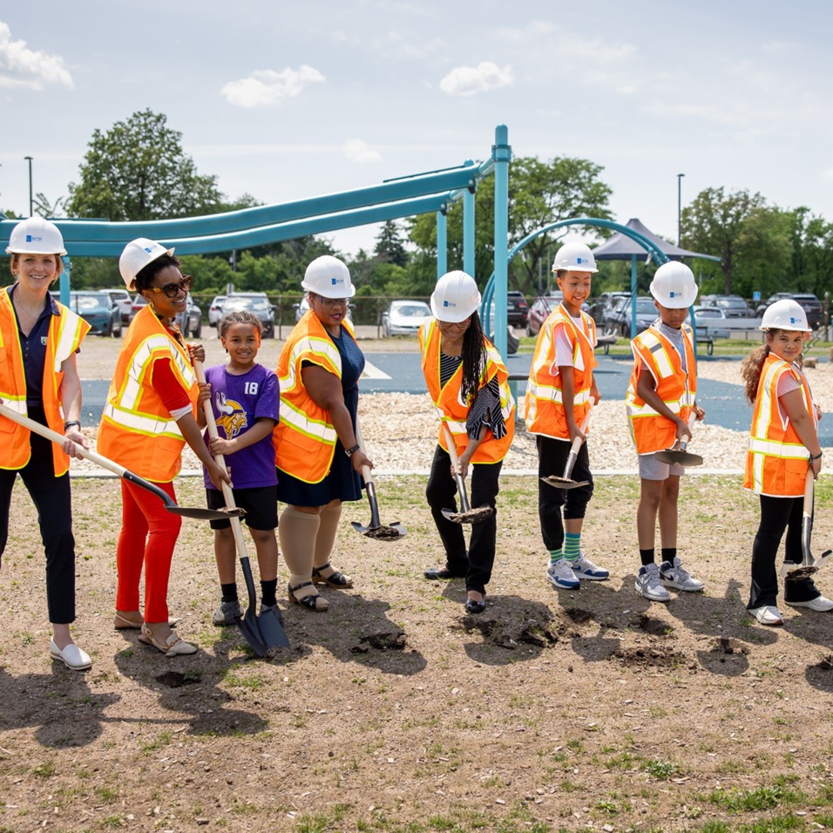 Kids in hard hats and orange vests breaking ground at a Trust for Public Land ceremony.