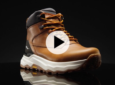 Brown hiking boot with orange laces and black ankle padding, shown on a reflective surface with a play button overlay.