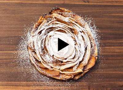 Apple pie on a wooden cutting board with video play button.