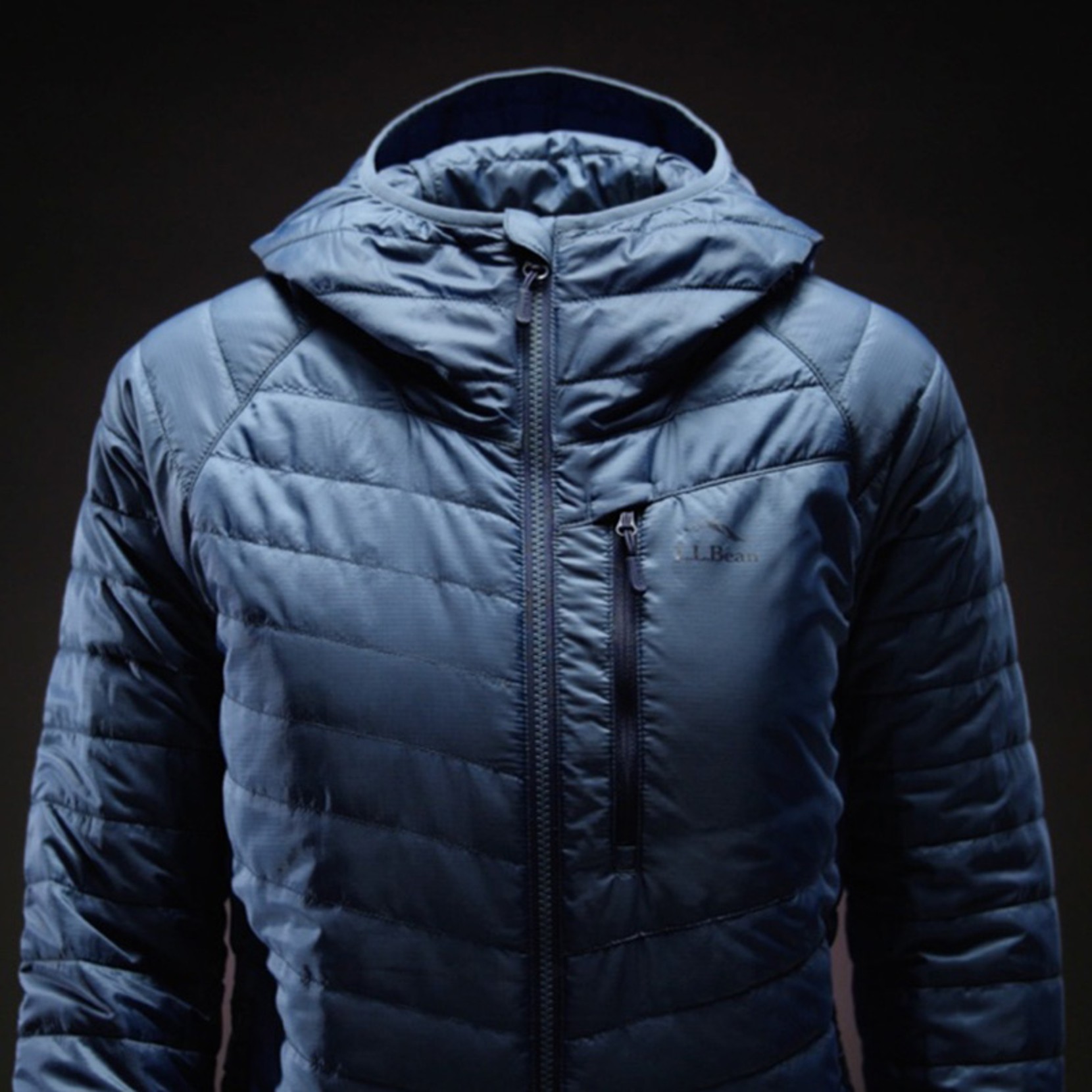 Blue L L Bean puffer jacket with hood shown against a dark background.