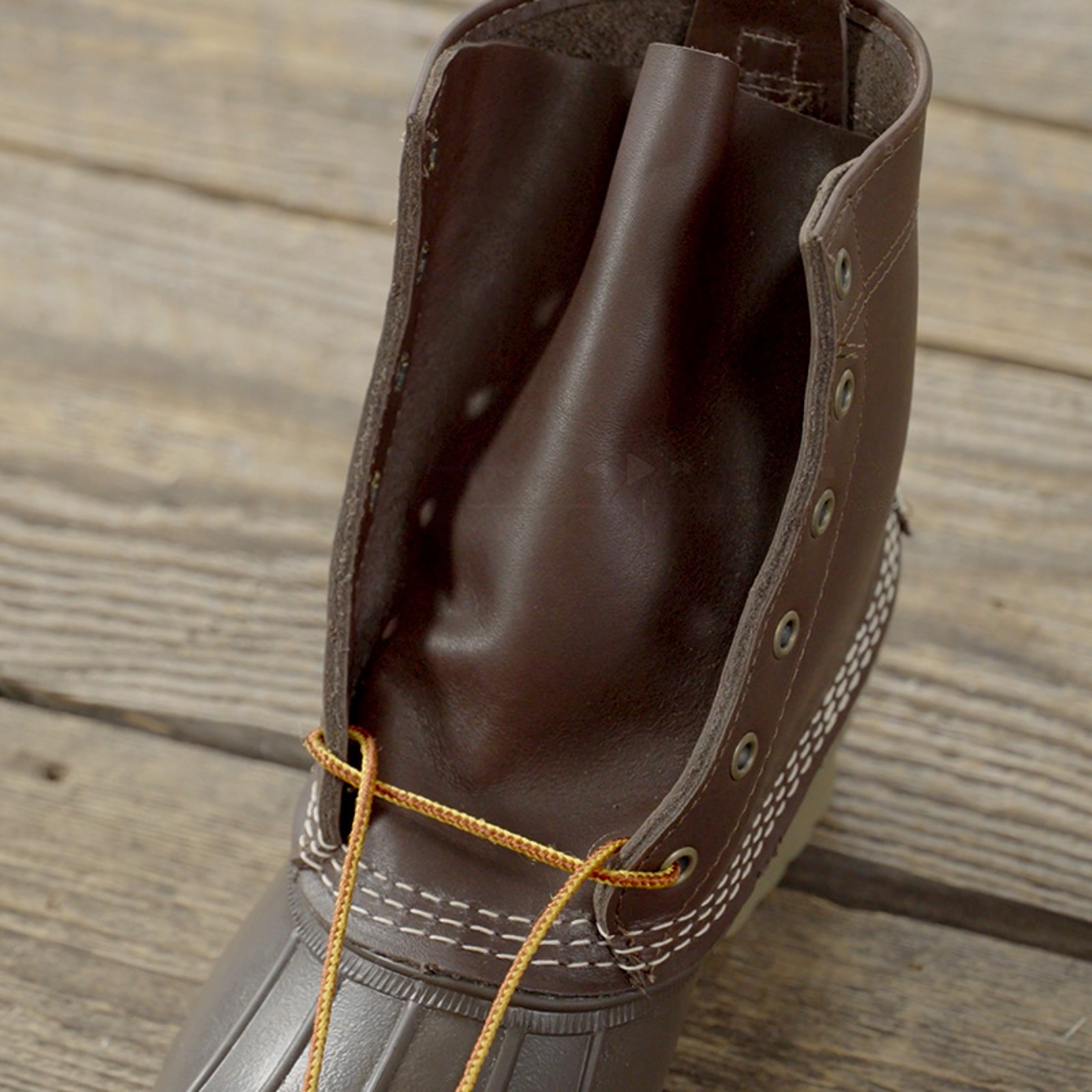 Close-up of brown boot with yellow laces, showing the start of lacing.