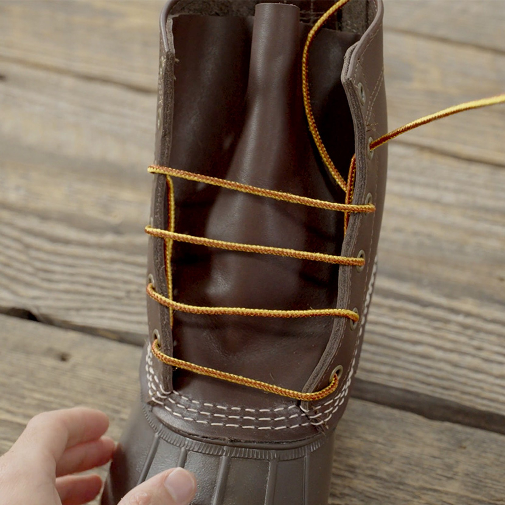 Brown boot with yellow laces fully threaded and partially tightened. 