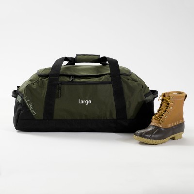 Large green L L Bean duffle bag with black straps, shown next to a tan Bean Boot.