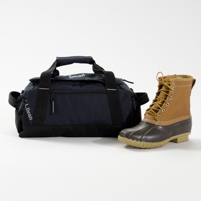Small navy L L Bean duffle bag with black straps, displayed beside a tan Bean Boot.