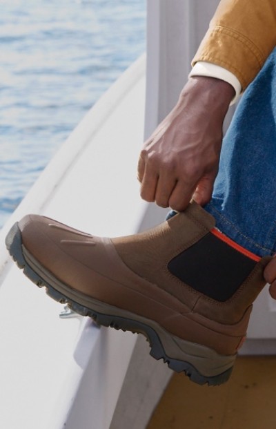 A person reaches down to adjust their wellie rain boot.