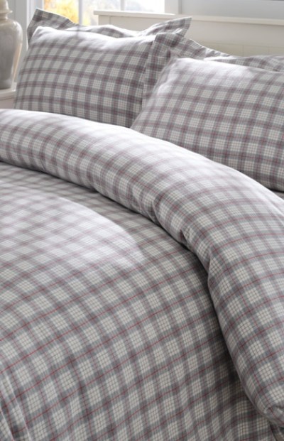 A neatly folded bed with matching plaid bedding and pillows.