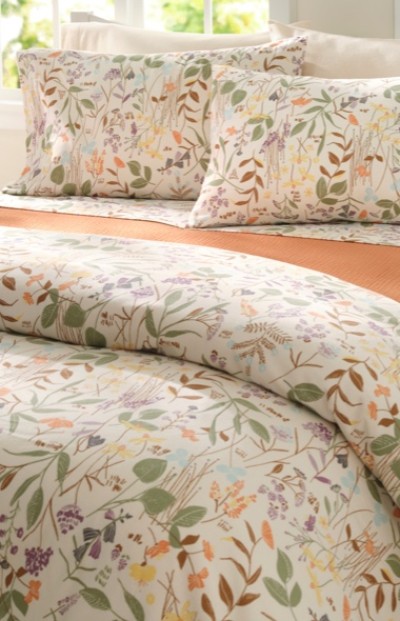 A neatly folded bed with an earth tone floral printed bedding.