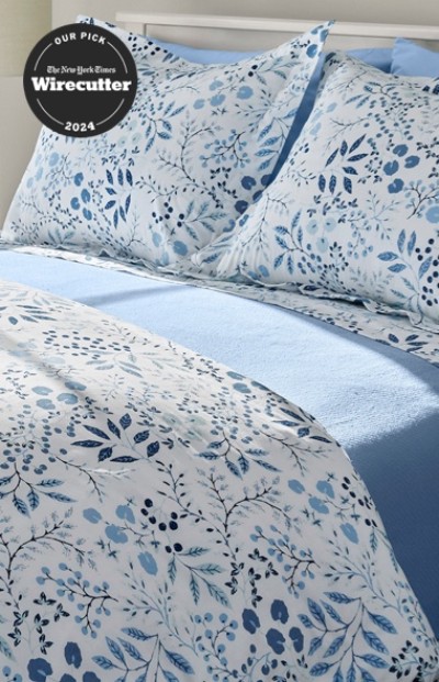 A neatly folded bed with matching blue and white floral bedding.