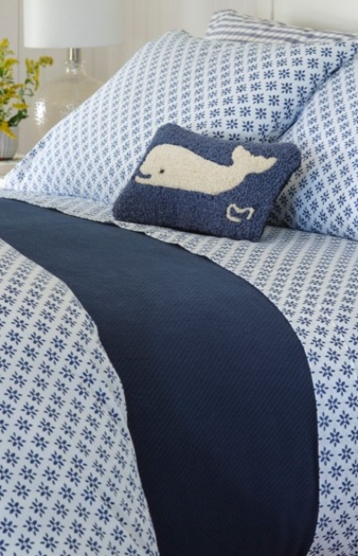 A neatly folded bed with matching blue and white patterened bed sheets.