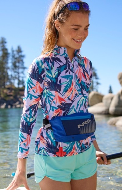 A woman stands knee deep in water holding a kayak paddle wearing a floral swim top and matching bottom.