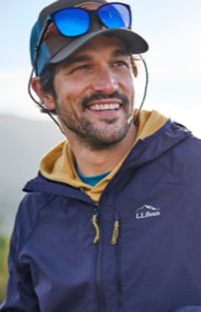 A man wearing a blue jacket with an L L Bean logo, a yellow hoodie underneath.