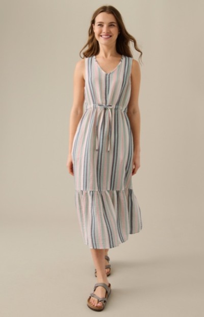 A woman wearing a sleeveless, striped dress with vertical pastel stripes and a tie at the waist.