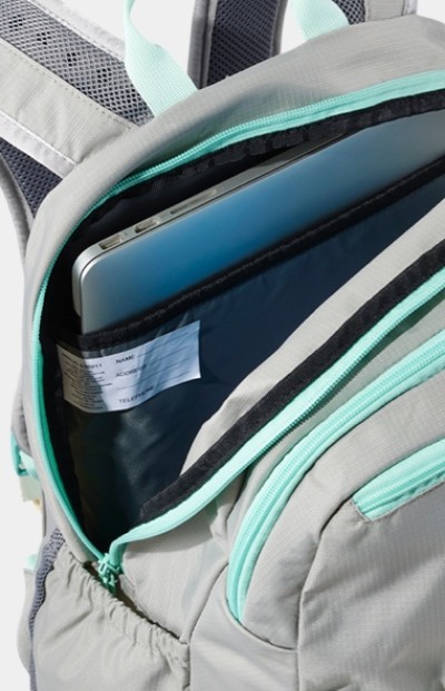 Close up of a gray L. L. Bean school backpack with the pocket unzipped showing a laptop inside.