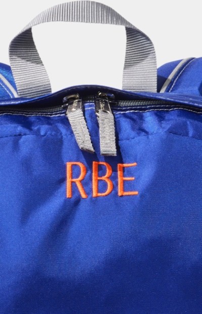 Close up of a blue L. L. Bean school backpack with the monogram R. B. E. in red block letters.