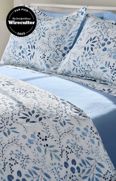 A neatly folded bed with matching blue and white floral bedding.