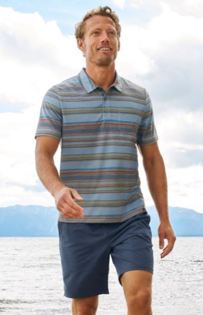 Man in a striped short-sleeve polo shirt and navy shorts, styled for a casual beachside look by the water.