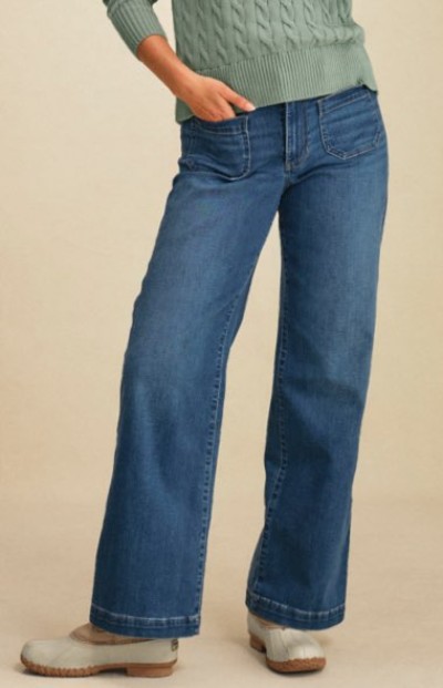 Cropped image of a person wearing wide-leg blue jeans, light green cable-knit sweater Bean boots.