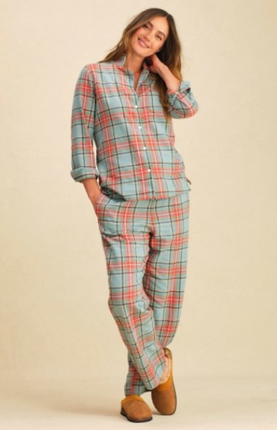 Person in light blue and pink plaid button-up matching pajama set and tan slippers stands against a neutral background.