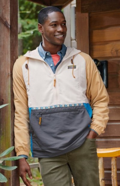 A man wearing a colorblock pullover jacket with tan sleeves, white top, blue accents, and a gray front pocket.