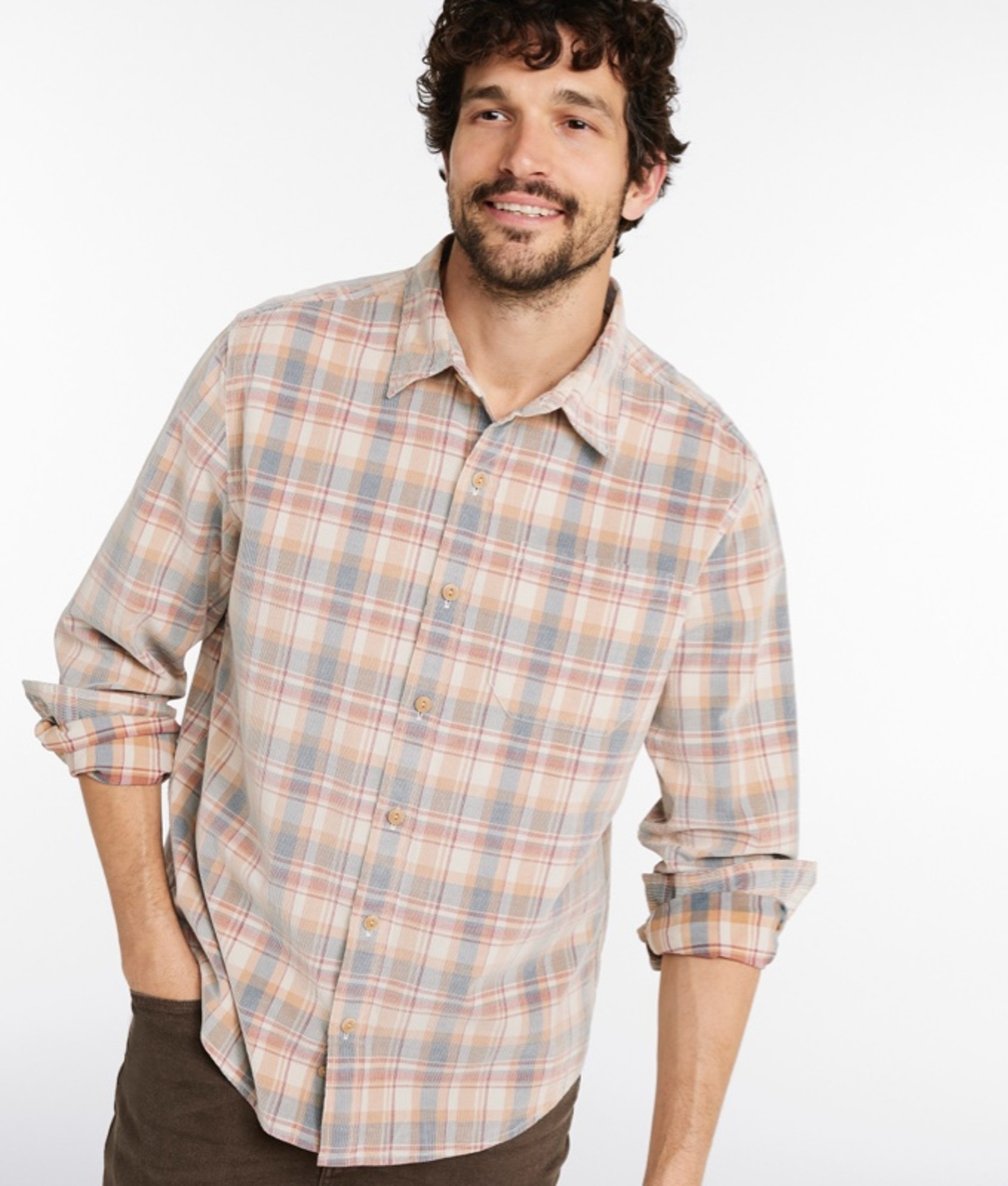 A thigh-up shot of a man wearing an untucked button-down shirt and pants.